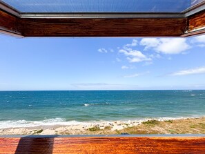 A view through a window with a wooden frame, overlooking a beach with the ocean and a clear sky. - Unique Beachfront Rustic House near Porto | Free Parking | Families & Friends (Apúlia)