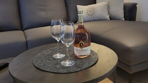 Un salon moderne avec un canapé, une table basse ronde, deux verres à vin et une bouteille de vin.