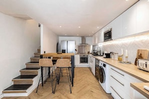 A modern kitchen with a central island, built-in appliances, and a wooden staircase. - Duplex Apartment with Pool a/c 2BR/4P - Cannes (Cannes)