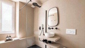 Ein modernes Badezimmer mit Duschkabine aus Glas, Waschbecken in Weiß, einem Spiegel und einer Toilette.
