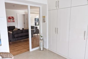 Ein modernes Wohnzimmer mit einer Couch, einem kleinen Tisch mit einer Pflanze und einer Schiebetür zum Küchenbereich.
