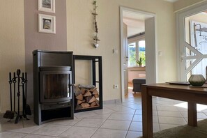 Ein Wohnzimmer mit Kamin, einem Esstisch und einer Tür zu einem anderen Raum.