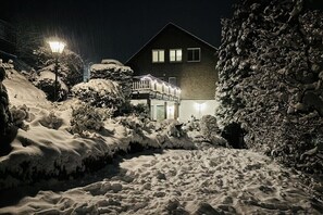 Schneebedeckte Landschaft mit einem Haus und einer beleuchteten Straßenlaterne.