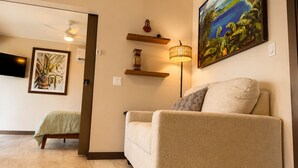 Una sala de estar con un sofá, un cuadro, una lámpara y un televisor.