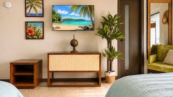A room with a bed, a wooden cabinet, a television, and wall-mounted artwork.