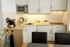 A compact kitchen with a microwave, sink, and a small dining area with two chairs. - Holiday apartment with 2 bedrooms (Cuxhaven)
