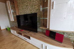 Ein modernes Wohnzimmer mit einem Flachbildfernseher, Holzschränken und einer Steinwand.