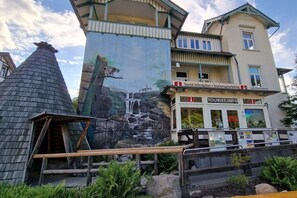 Ein Gebäude mit einem Wandbild, das einen Wasserfall und Wildtiere zeigt, sowie ein Touristeninformationszentrum und eine traditionelle Holzkonstruktion.