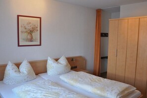 Ein Schlafzimmer mit zwei Betten, einem Holzschrank und einem gerahmten Bild an der Wand.