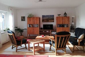 Ein Wohnzimmer mit Holzmöbeln, einem Fernseher und einem Bücherregal.