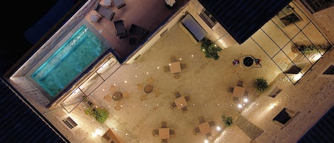 Un área de piscina en la azotea con sillones reclinables, una piscina pequeña y mobiliario de exterior.