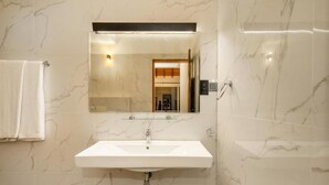 A bathroom with a white sink, a mirror, and marble walls. - The Cloud Hanthana Kandy (Kandy)