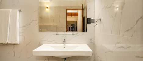 A bathroom with a white sink, a mirror, and marble walls.