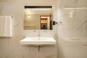A bathroom with a white sink, a mirror, and marble walls.