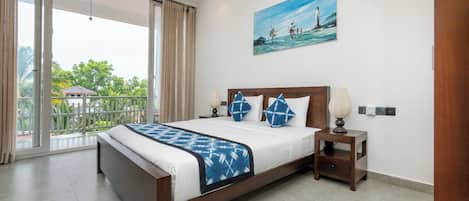 A modern hotel room with a large bed, a painting, a nightstand, and a view of greenery through the window.