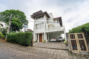 Une maison à deux étages avec une allée couverte et une voiture garée à l’intérieur.