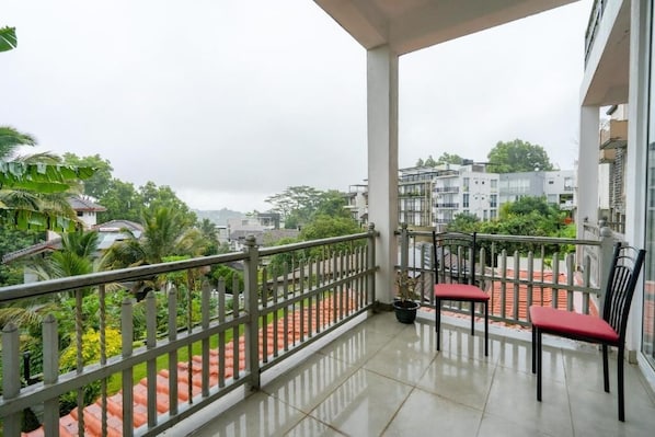 Un balcon avec une balustrade, deux chaises et un pot de fleurs.