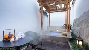 Un área de spa con un jacuzzi, una mesa con velas y una pérgola de madera.