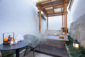 Uma área de spa com hidromassagem, uma mesa com velas e uma pérgula de madeira.