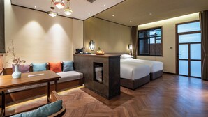 A hotel room with a wooden floor, a bed, a sofa, a desk, and a small fireplace. - Deefly Origin House Wuyi (Jinhua)