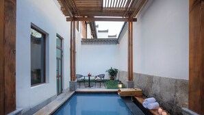 A serene indoor pool area with a wooden bench, a table with chairs, and a small garden. - Deefly Origin House Wuyi (Jinhua)