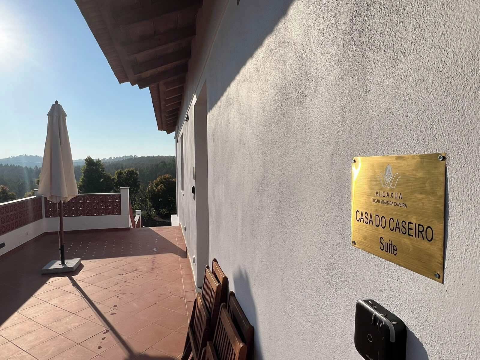 Um terraço com vista, uma placa indicando 'CASA DO CASEIRO Suite' e um interfone.