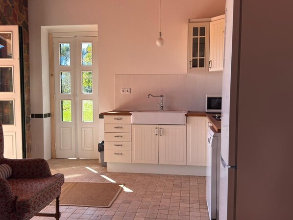 A kitchen with white cabinets, a sink, and a microwave.