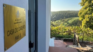 Une entrée d’immeuble avec une pancarte indiquant « CASA DO CASEIRO, app. 3 » et une vue sur un vignoble.