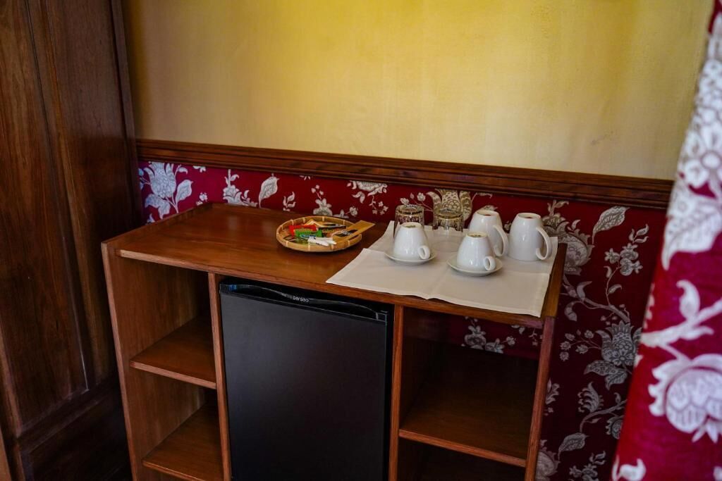 Eine kleine Küchenzeile mit Kühlschrank, einem Tisch mit einer Speiseplatte und einem Satz weißer Tassen und Untertassen.