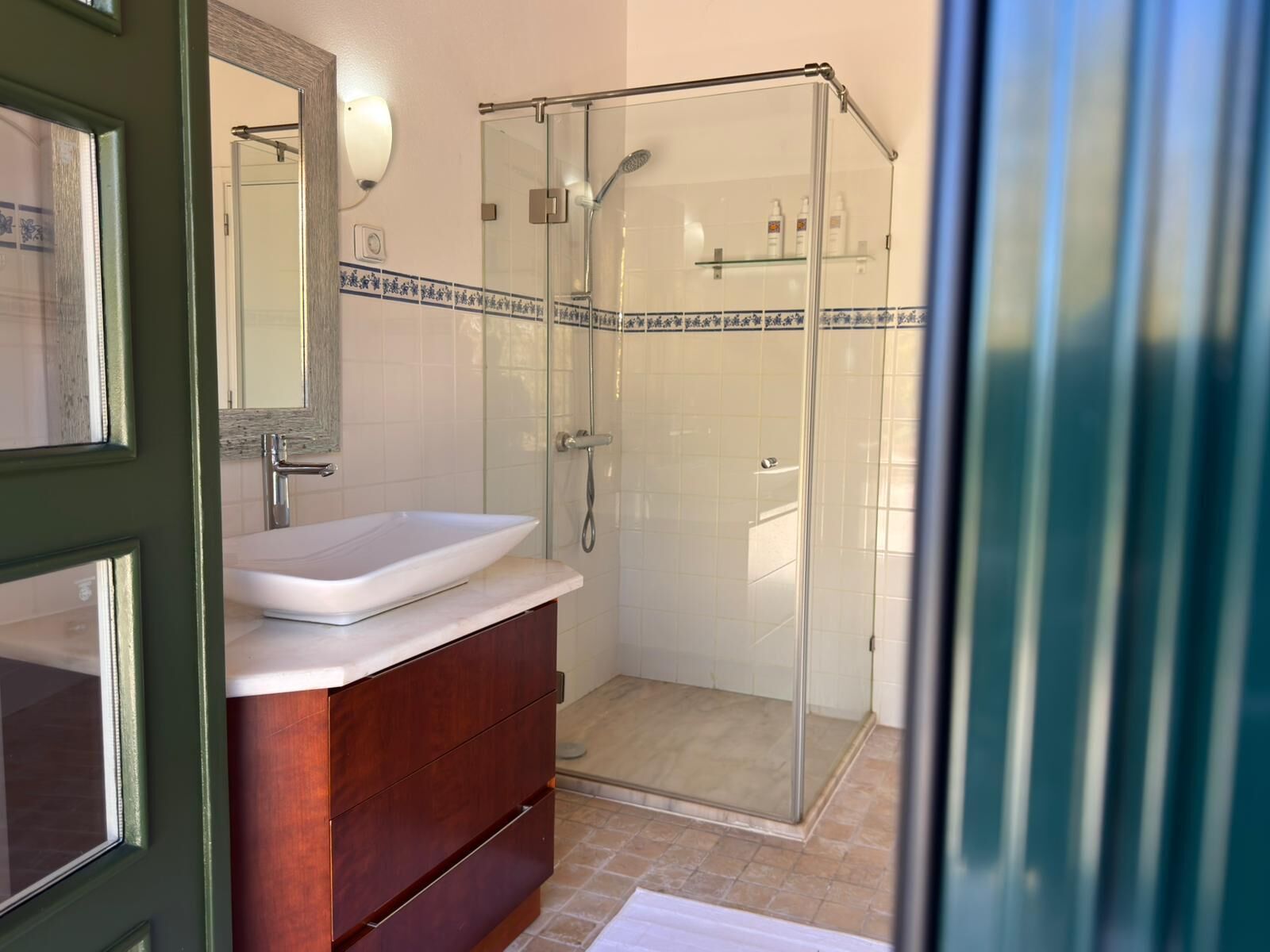 A bathroom with a glass-enclosed shower, a white sink, and a wooden vanity.