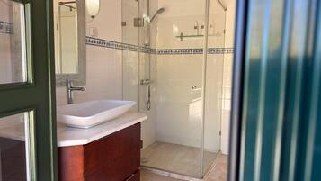 A bathroom with a glass-enclosed shower, a white sink, and a wooden vanity.