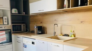 Eine moderne Küche mit weißen Schränken, einer eingebauten Mikrowelle, einem Geschirrspüler und einem schwarzen Induktionskochfeld.