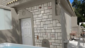 Un espace piscine agrémenté d’une porte blanche, d’un mur en pierre et de mobilier d’extérieur.
