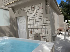 A pool area with a white door, a stone wall, and outdoor furniture. - Doliva Studio 6 Apartment with Private Pool (Achillii)