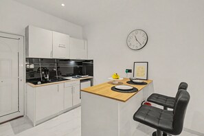 A modern kitchen with white cabinetry, a black stove, and a wooden countertop. - Doliva Studio 6 Apartment with Private Pool (Achillii)