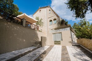 A building with a stone facade, a set of stairs leading to a door labeled 'DOLIVA,' and a covered outdoor seating area. - Doliva Studio 6 Apartment with Private Pool (Achillii)