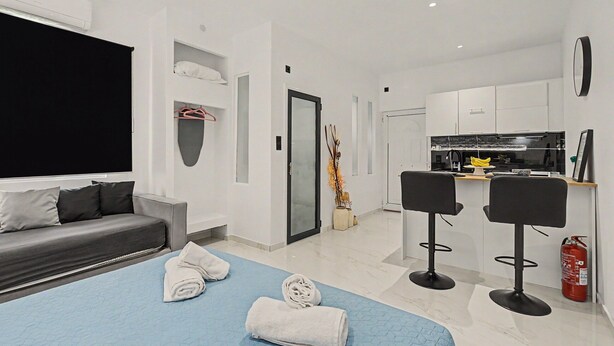 Une chambre d’hôtel moderne équipée d’un lit, d’un canapé, d’une télévision, d’une kitchenette et d’une salle de bain.