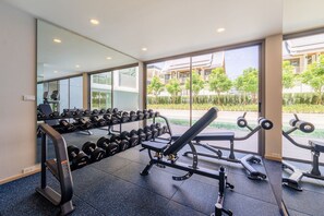 Ein Fitnessstudio mit Trainingsgeräten, einer Langhantelbank und Kurzhanteln.