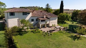A two-story house with a tiled roof, a patio with outdoor furniture, and a garden with various plants. - Villa Molamezza by MMega (Mercatale in Val di Pesa)