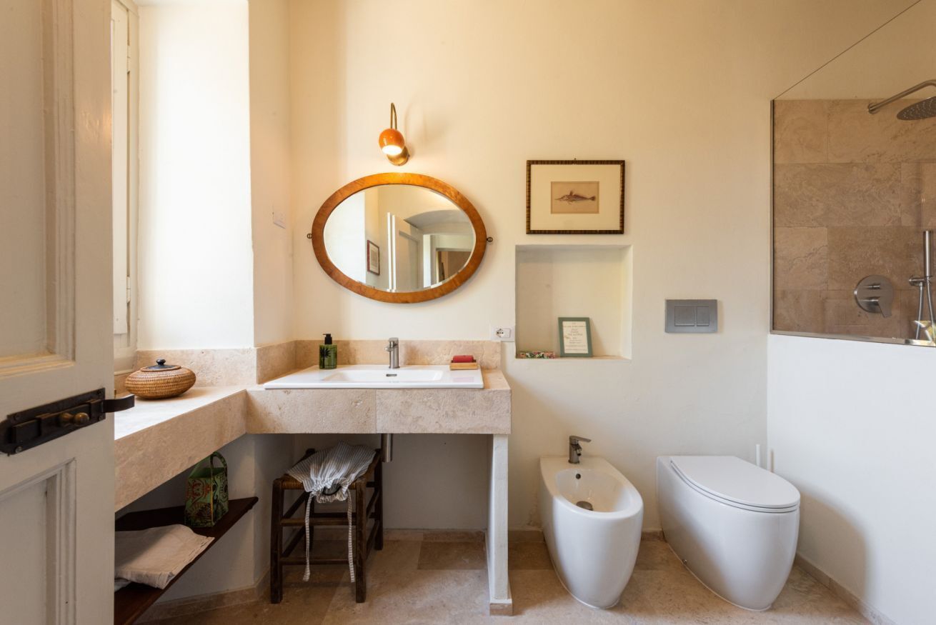 A bathroom with a sink, mirror, toilet, and shower.