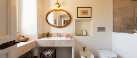 A bathroom with a sink, mirror, toilet, and shower.