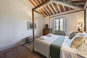 A bedroom with a four-poster bed, a radiator, a window, and a lamp. - Villa Molamezza by MMega (Mercatale in Val di Pesa)