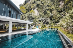 Una piscina al aire libre, sombrillas, sillones reclinables de piscina
