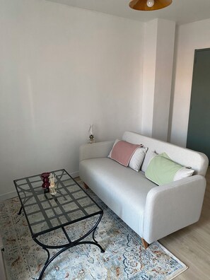 A living room with a sofa, a glass coffee table, and a patterned rug. - Cozy Studio (Avignon)