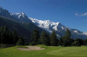 Un parcours de golf avec une chaîne de montagnes en toile de fond.