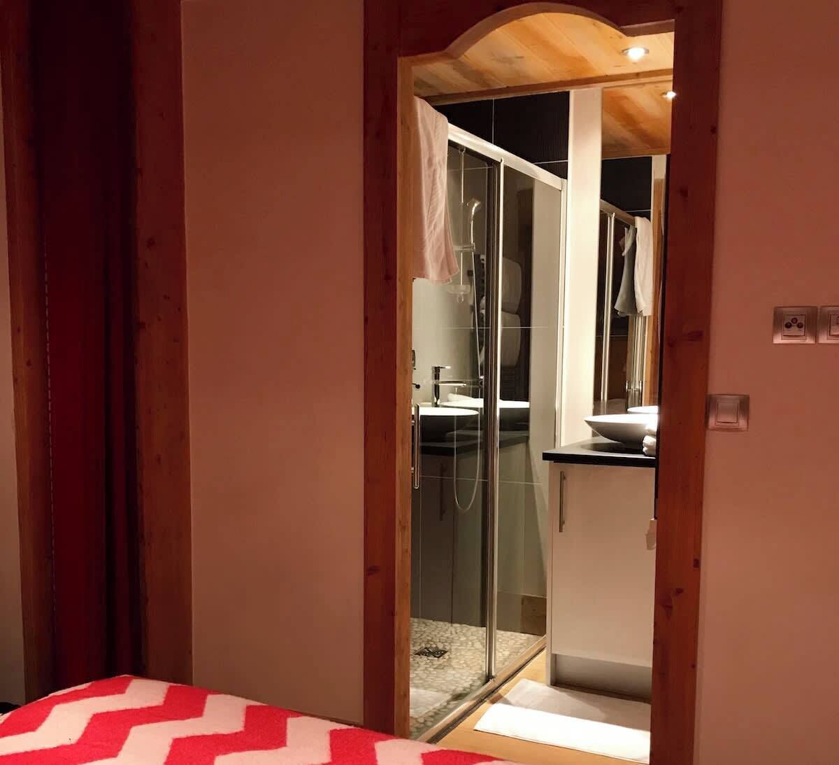 The master ‘red’ bedroom‘s en-suite has a large shower and basin.