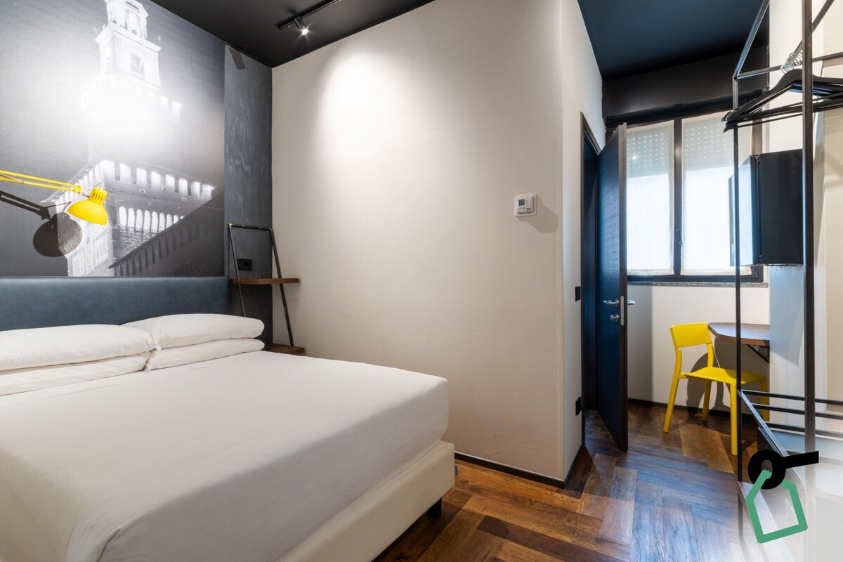 Un dormitorio con cama, escritorio, silla y ventana.