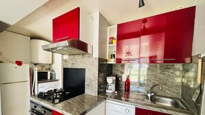 A kitchen with red cabinets, a stove, a microwave, a dishwasher, and a sink.