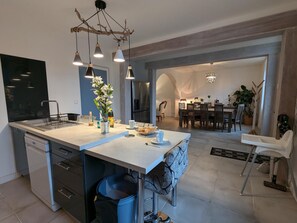 A modern kitchen with a central island, pendant lighting, and a dining area with a chandelier. - Large house, pets allowed - 8 guests (Jarnac)