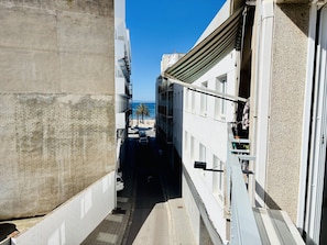 A narrow alleyway between buildings with a clear view of a beach and palm trees in the distance. - Central apartment in Roses - 4 guests (Roses)